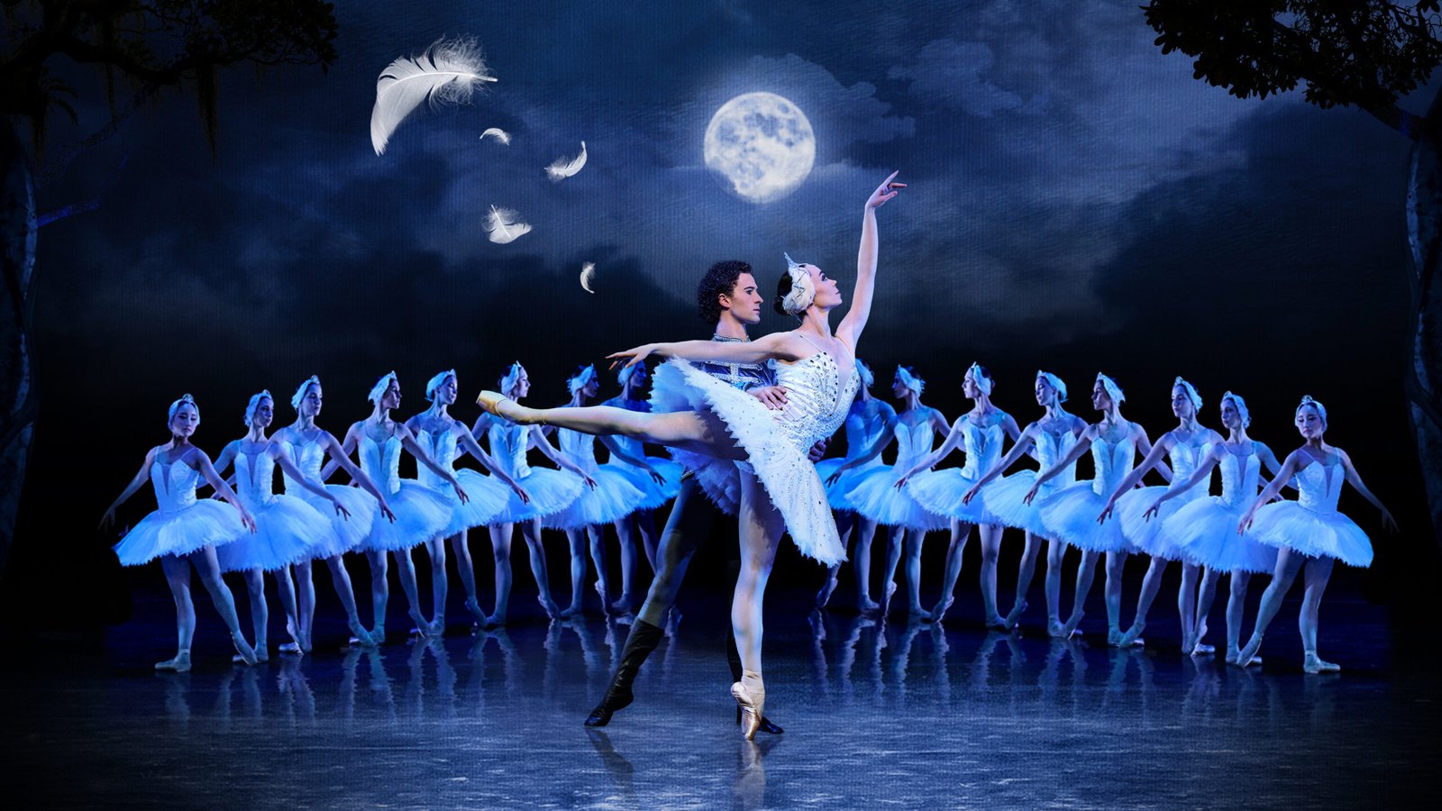 A pair of ballet dancers perform a lift on a blue-lit stage, surrounded by a chorus of tutus beneath a moonlit backdrop.